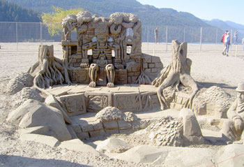 Abstract sand sculpture of a skeleton man sitting on a wall