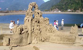 Abstract sand sculpture of a winged women, a child, and an abstract pile of skulls