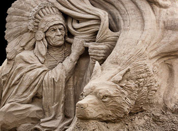 Sculpture of an elderly man wearing a headdress staring at an abstract wolf
