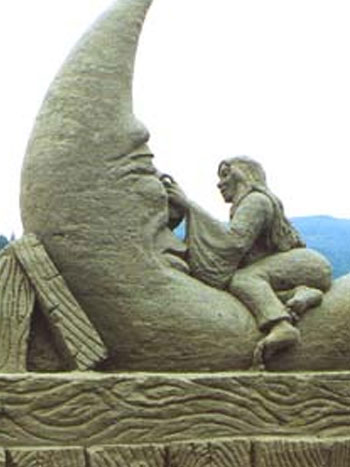 Sand sculpture of a women laying on top of a personified moon