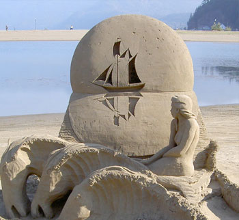 Sculpture resembling the ocean with a sailboat casting a reflection across the water