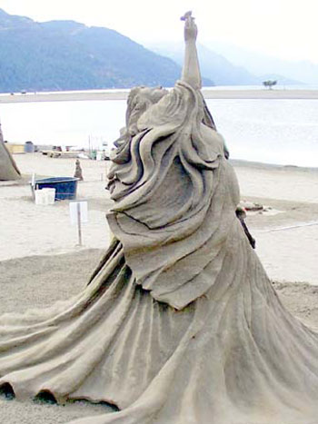 Sand Sculpture of a person reaching straight up into the sky