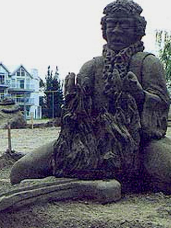 Abstract sand sculpture of a person staring down at many small people