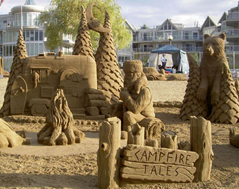 Large sculpture of a campsite in which a man sits by a fire while a bear looks on from the edge of the campsite