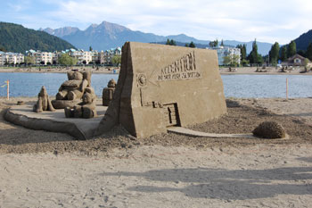 Large abstract sand sculpture depicting a small animal approaching a large wall