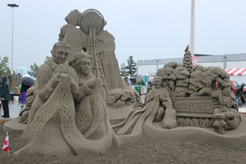 Sand sculpture of three people using cellphones with a data tower in the background